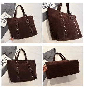 Macro view of dark brown suede tote bag with metallic stud details and heart charm