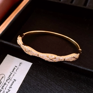 Détail d'un bracelet doré 18K avec motif matelassé et diamants sur plateau noir