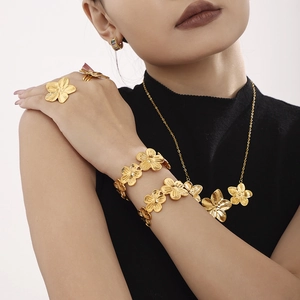 Gold flower jewelry set with necklace bracelet and rings on a model with black top