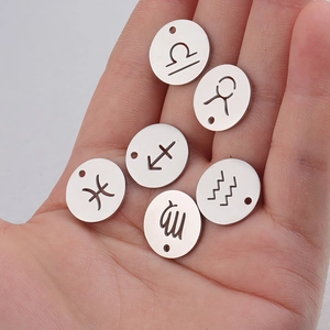 Detailed close-up of six silver zodiac sign charms on a palm for jewelry DIY