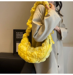 Detail view of bright yellow quilted cloud bag featuring a textured ruched shoulder strap