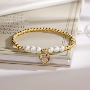 Detail of gold beads and white pearls bracelet with a colorful zircon heart pendant