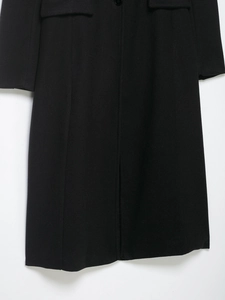 Detail of wool coat fabric texture, pocket flap and hem on black mid-length overcoat
