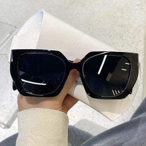 Detail of black square oversized sunglasses with a white faux leather foldable case