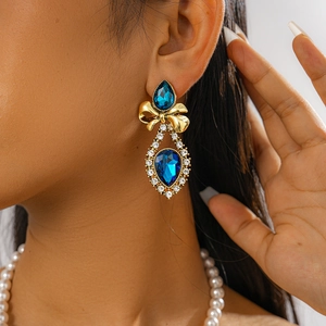 Close-up of vintage bow earrings with blue teardrop gemstone and sparkling rhinestones
