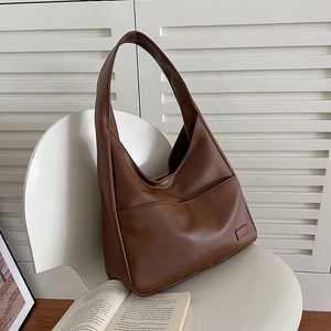 Braune minimalistische große Tote Bag aus PU-Leder auf weißem Stuhl für Pendler