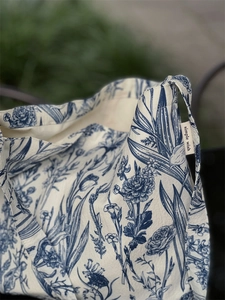 Close-up of vintage blue botanical print on beige canvas tote bag with simple wish tag