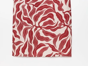 Macro detail of red leaf print fabric with precise stitching on midi dress hem