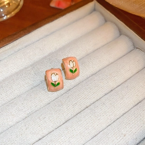 Close-up of pink enamel tulip earrings in a beige velvet jewelry display box