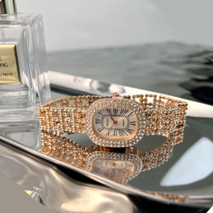 Close-up of rose gold oval quartz watch with diamond-encrusted bezel and Roman numerals