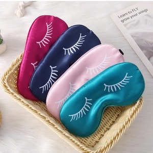Detailed view of four colorful silk sleep masks with eyelash prints in a woven basket