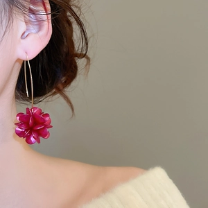 Dettaglio dell'elegante orecchino a fiore rosso con gancio dorato su una modella