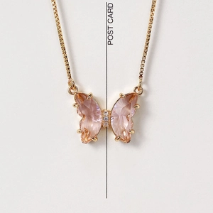 Detailed macro view of a pink crystal butterfly pendant on a 18K gold-plated chain