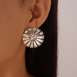 Close-up of a silver sunburst geometric earring on a model with a polished finish
