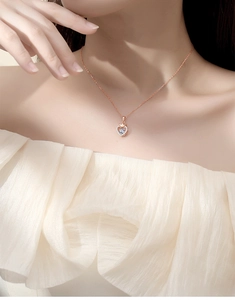 Detail of rose gold heart crown necklace with a dancing stone on a female model