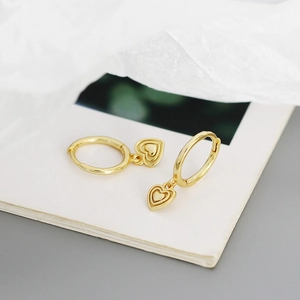 Macro view of gold S925 silver heart hoop earrings on a minimalist white aesthetic backdrop