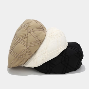Close-up of quilted checkered texture on stylish khaki, white, and black beret hats