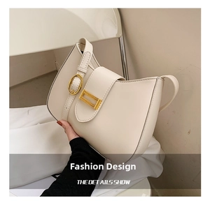 Close-up of cream white baguette bag featuring gold buckle and textured leather detail