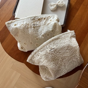 Elegant beige lace embroidery makeup bags with floral mesh on a wooden table