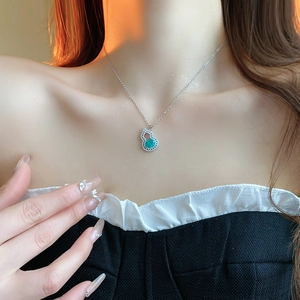 Macro view of Chinese style silver gourd necklace with emerald zircon on model's neck