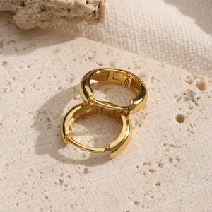 Detailed close-up of S925 sterling silver gold-plated hoop earrings on a stone base