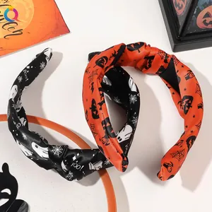Detail of Halloween knotted headbands with pumpkin and ghost patterns on white surface