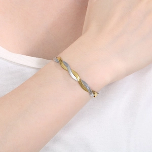 Close-up of a two-tone gold and silver twisted snake chain bracelet on a wrist