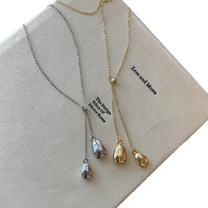 Minimalist 18k gold and silver plated bean pendant necklaces on a book cover