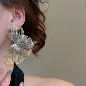 Gros plan de grandes boucles d'oreilles fleurs ajourées montrant l'artisanat du métal