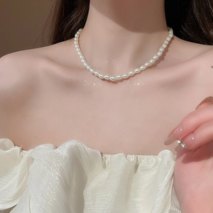 Close-up of elegant white pearl necklace on model's neck for a minimalist French style