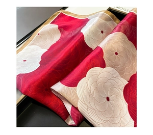 Macro detail of silk scarf showing red camellia floral print and satin texture