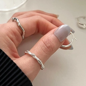 Detailed view of woven S925 sterling silver rings and hoops worn on fingers