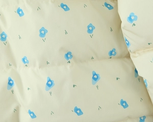 Macro detail of quilted floral fabric with blue patterns on a beige winter coat