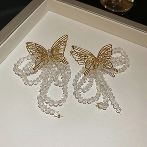 Detailed close-up of golden hollow butterfly earrings with crystal tassel drops