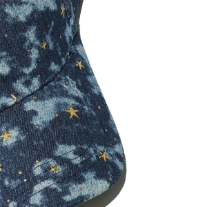 Detailed macro view of denim baseball cap with gold star prints and washed texture