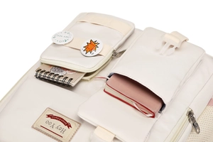 Detail of cream backpack showing multiple storage pockets, buckles, and zipper compartments