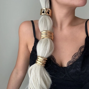 Detail of golden metal hair cuffs styled on braided hair for elegant hairstyles