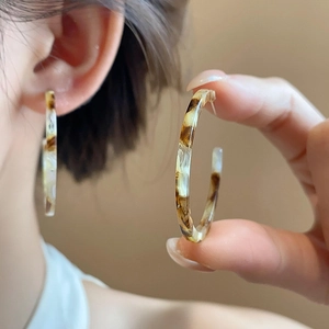 Detail view of retro resin C-shaped hoop earrings with amber tortoiseshell texture on model