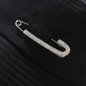 Macro shot of silver-plated safety pin brooch with white rhinestones on a black sun hat