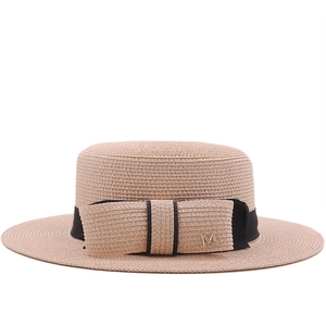 Flat top straw boater hat with black ribbon, bow detail and golden M charm for beach vacation