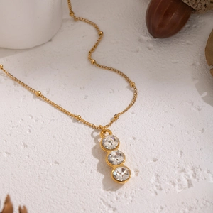 Close-up of golden minimalist Y-necklace with three vertical clear cubic zirconia stones