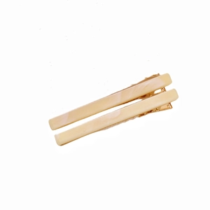 Detail of two beige marble acetate hair clips with golden metal bases on white background