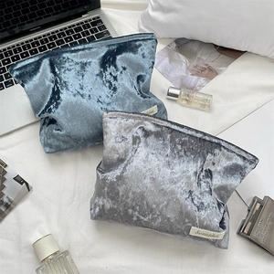 Close-up of velvet makeup bags in grey and blue with soft texture and side label