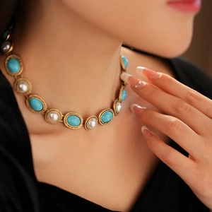 Detail of vintage necklace with turquoise stones and round pearls on a gold chain