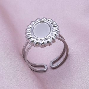 Close-up of silver open ring with sunflower relief design and gray inlay on silk