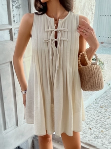 Detail of beige sleeveless dress with pleated texture and stylish neck tie design
