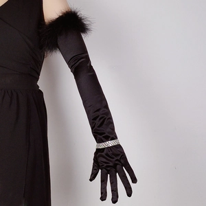 Detail of elegant black long satin gloves with soft feather trim on the upper arm cuff