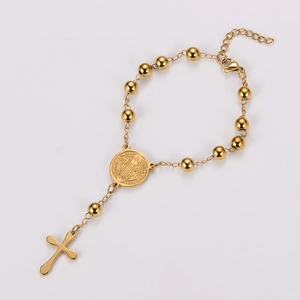 Detailed close-up of golden rosary bracelet with Saint Benedict medal and cross pendant
