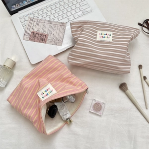 Detail of striped canvas toiletry bags with zipper and branded label in a lifestyle setting