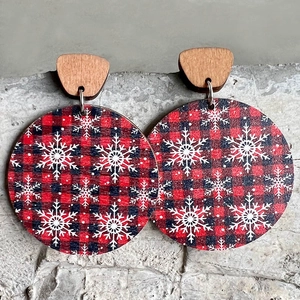 Macro detail of wooden Christmas earrings with red and black buffalo plaid and white snowflake